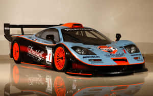 一輛藍黑McLaren賽車配橙色輪圈，在博物館展示，地板有倒影。 — Steam Deck 壁紙