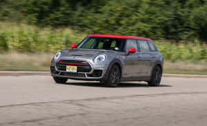 銀色MINI Cooper紅色車頂在道路上飛馳，背景綠色模糊。 — MacBook Pro 13 壁紙