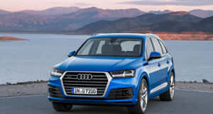 日落時分，藍色 Audi Q7 SUV 停泊在湖邊，背景是山脈。 — Audi R8 GIF 壁紙