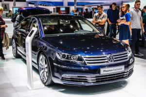 閃亮的藍色Volkswagen Phaeton Exclusive房車在車展上展出，附近有與會者。 — Surface Pro 壁紙