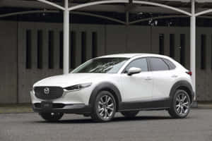 白色Mazda CX-30 SUV停放在現代簷篷結構下。 — MacBook Pro 14 壁紙