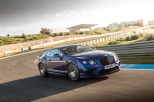 藍色 Bentley 在日落時分的賽道上奔馳，帶有模糊動態效果。 — Surface Pro 壁紙