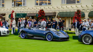 草地上藍色Pagani Huayra跑車，人群和攝影師。 — 日落 壁紙