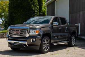 深灰色 GMC Canyon 皮卡車停在有常春藤的木製車庫旁。 — MacBook Air M2 壁紙