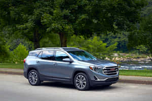 銀色GMC Terrain SUV停泊在河邊，背景有樹木。 — Surface Pro 壁紙