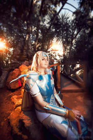 穿著藍色奇幻盔甲的cosplayer在森林的夕陽下坐在岩石上。 — 小米18 Fold 壁紙