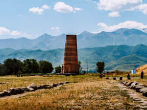 草地上的古老磚塔，背景有山脈 — 建築 壁紙