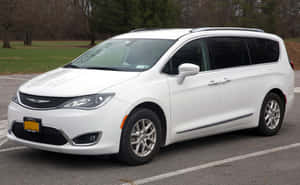 白色 Chrysler Pacifica 小型貨車停泊在停車場，後面有樹木和草地。 — Steam Deck 壁紙