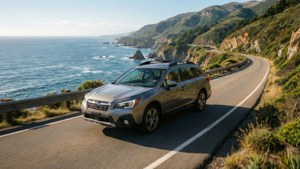 銀色Subaru SUV在海岸公路上行駛，有海洋和懸崖