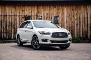 白色 Infiniti QX60 SUV 停放在風化的木製穀倉前。 — MacBook Air 13 壁紙