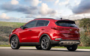 紅色Kia Sportage SUV停泊在路邊，背景有丘陵和多雲的天空。 — Steam Deck 壁紙