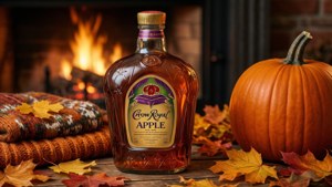 Crown Royal Apple 威士忌酒瓶與南瓜和秋葉放在壁爐旁。