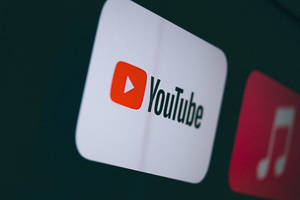 YouTube 應用程式圖示在黑暗的數位螢幕上發光，附近有一個音樂應用程式圖示。