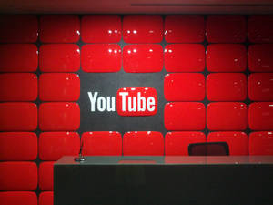 接待桌後方的紅色播放按鈕瓷磚牆上的 YouTube 標誌。 — 紅色 壁紙