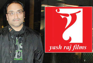 戴眼鏡、穿黑色外套的男子站在Yash Raj Films標誌旁。