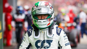 穿著AlphaTauri裝備的F1車手在賽道上看著鏡頭。