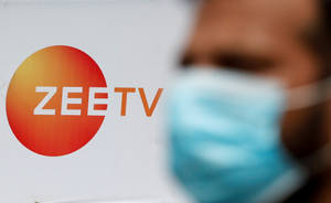 一個戴住藍色口罩嘅人企喺Zee TV標誌附近。