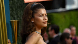 Zendaya 在正式活動中穿著迷人的晚裝，身後有綠植。