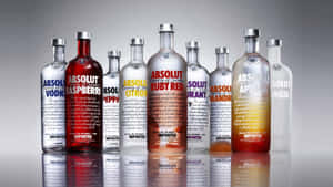 一排帶有彩色標籤的Absolut伏特加酒瓶在反射表面上。