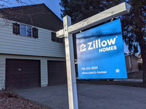 Zillow Homes房地產標誌在一棟有兩個車庫門的房子前。