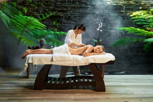 一位女性在寧靜的水療中心接受按摩，周圍有瀑布和蕨類植物。