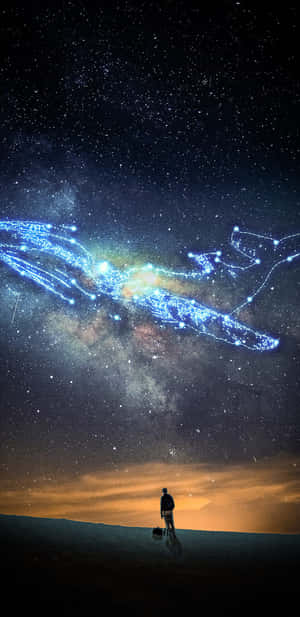 一個人獨自站在沙漠沙丘上，下方是發光的藍色星系和星空。 — 夜空 壁紙