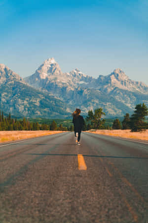 一個人在鋪砌的道路上跑步，背景有山脈。 — 跑步 壁紙