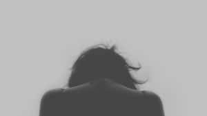 深色頭髮嘅人將頭低向純灰色背景。 — 悲傷女孩 壁紙