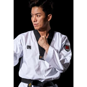 一名身穿白色制服、繫黑帶的男性跆拳道選手，握拳擺出姿勢。 — 1:1 壁紙