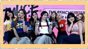 七位K-pop女孩在帶有「TWICE」品牌的粉紅色舞台上快樂地擺姿勢。