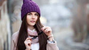 戴紫色冷帽和米色外套的女性在戶外手持太陽眼鏡。 — 淺紫色美學動態圖 壁紙
