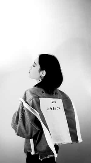 一位身穿背後有文字的牛仔外套的女性，側身站立。 — 黑色美學 壁紙