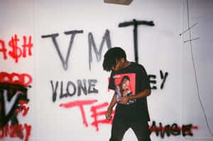 年輕男子留著辮子頭，在佈滿塗鴉的房間裡身穿黑色T恤。 — Playboi carti GIF 壁紙