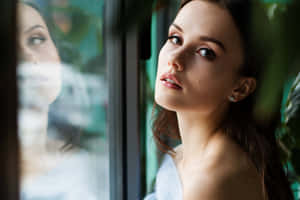 女人望向窗外，玻璃上有模糊倒影