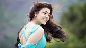 一位長髮棕色的女子，身穿藍綠色連衣裙，在戶外微笑。 — 微笑 壁紙