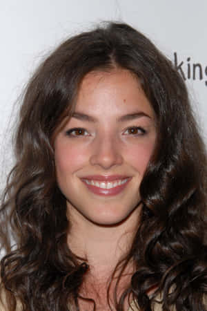 擁有波浪形棕色頭髮的年輕女性對著鏡頭微笑 — 蘇菲亞公主 壁紙