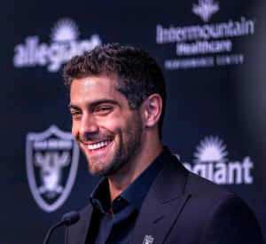 一位微笑的男士身穿西裝出席記者會，身後有團隊標誌。 — NFL 美式足球 GIF 壁紙
