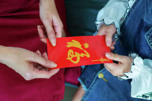在文化慶祝活動中，成年人將帶有金色文字的紅色利是封送給小孩。 — 中文 壁紙