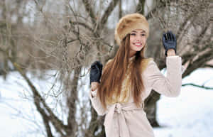 穿著冬季外套和毛帽的女士在雪景中微笑。 — 冬日美學 壁紙