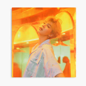 穿藍色襯衫的年輕人在溫暖的橙色照明室內向上看。 — Jimin GIF 壁紙