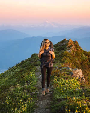 遠足者在山徑上欣賞夕陽，背景有白雪覆蓋的山峰 — 4:5 壁紙
