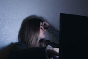 疲憊的女性在夜間使用筆記型電腦時將頭靠在牆上休息。 — 悲傷女孩 壁紙