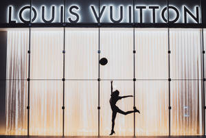 夜晚在 Louis Vuitton 商店前跳躍的舞者剪影。 — 路易威登 壁紙