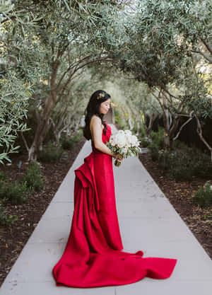 一位身穿紅色長裙的新娘，手持白色花束，穿過花園小徑。 — 權力遊戲 第八季 壁紙