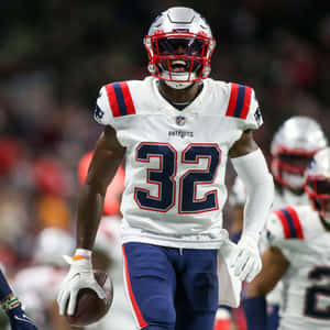 身穿愛國者隊球衣的美式足球員在夜間比賽中帶球奔跑。 — NFL 美式足球 GIF 壁紙