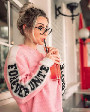 身穿粉紅色毛衣的女性在室內用吸管啜飲飲料 — 熱粉紅美學 壁紙