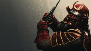 身穿紅金盔甲的武士武士，手持武士刀，頭盔下的臉孔充滿威嚇。 — 武士 壁紙