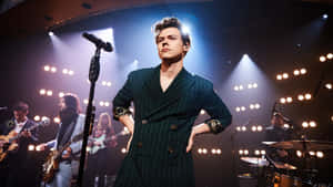 身穿綠色西裝的歌手在舞台上與樂隊和明亮燈光現場表演。 — 紐約市 壁紙