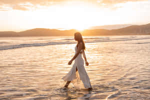 穿白色連衣裙的女子在金色日落時在海中行走 — 夏日氣息 壁紙