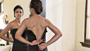 女性一邊照鏡子一邊調整黑色連衣裙的拉鍊。 — 白色美學gif 壁紙